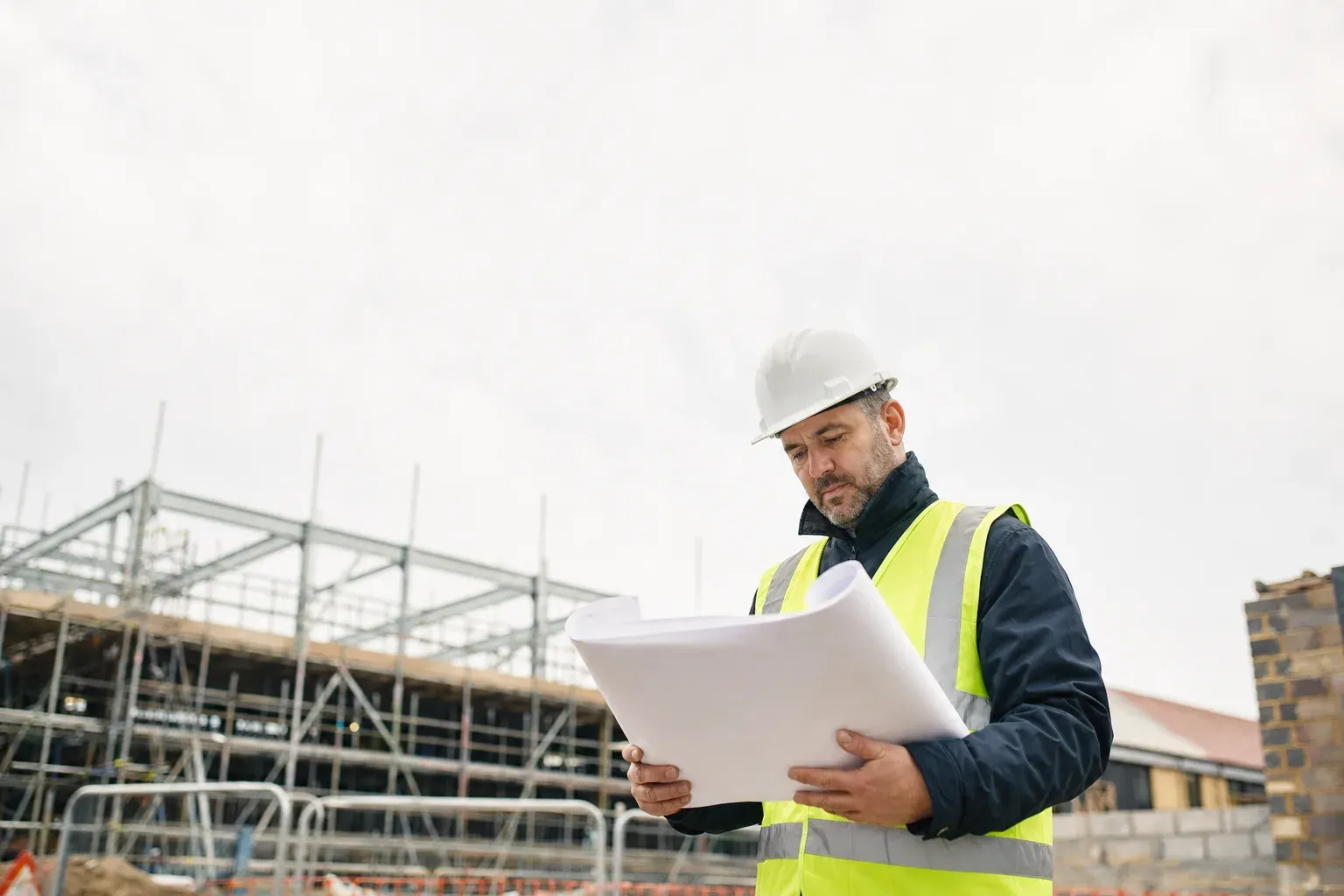 A site manager reviewing drawings on a UK construction site.